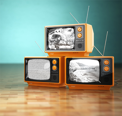 Three old style TV's with black and white screens. Two are on the bottom and one is sitting on top of them.