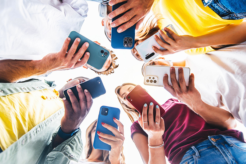 A group of people holding their phones. The photo is taken looking up and they are in a ring.
