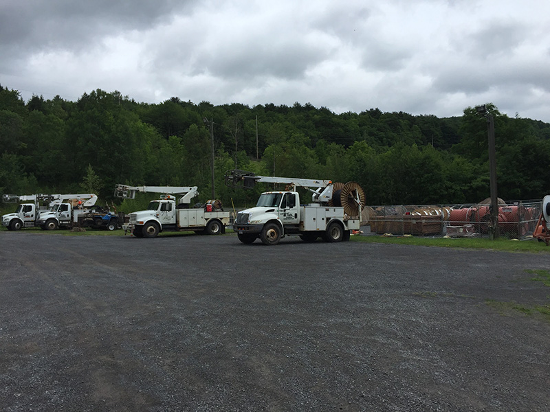 Four MTC bucket trucks are lined up under a cloudy sky.