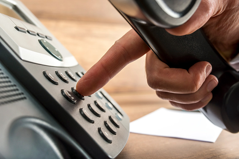18-3-blog-feature-1 a person holding a phone and pressing the 5 key on the receiver.