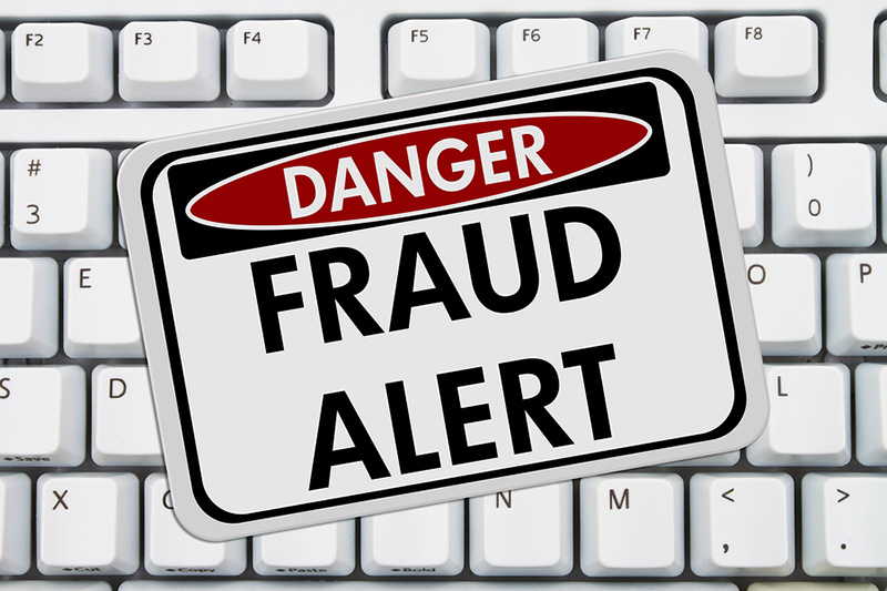 A sign on a keyboard reads Danger Fraud Alert.